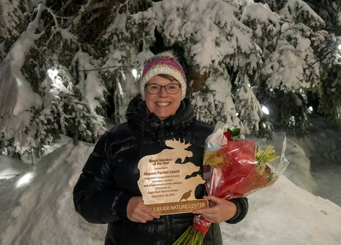 A woman is holding a trophy and flowers in the snow.