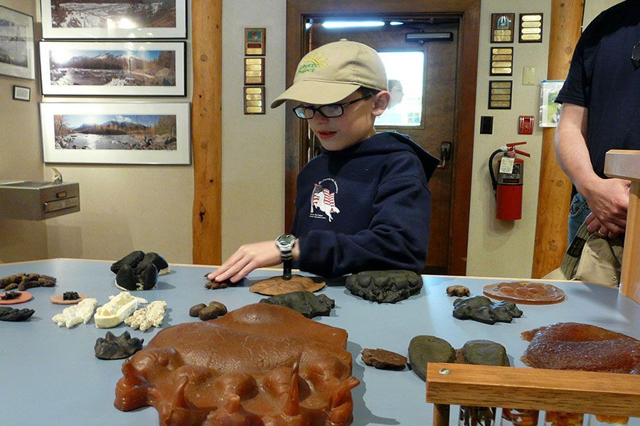 A young boy wearing a hat and glasses is playing with rocks on a table