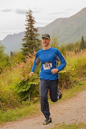 A man is running on a dirt path in the mountains.