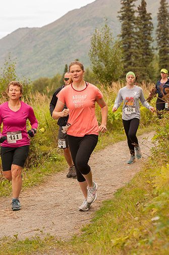 A group of women are running down a dirt path.