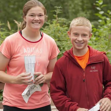 A woman wearing an adidas shirt stands next to a boy wearing a red jacket