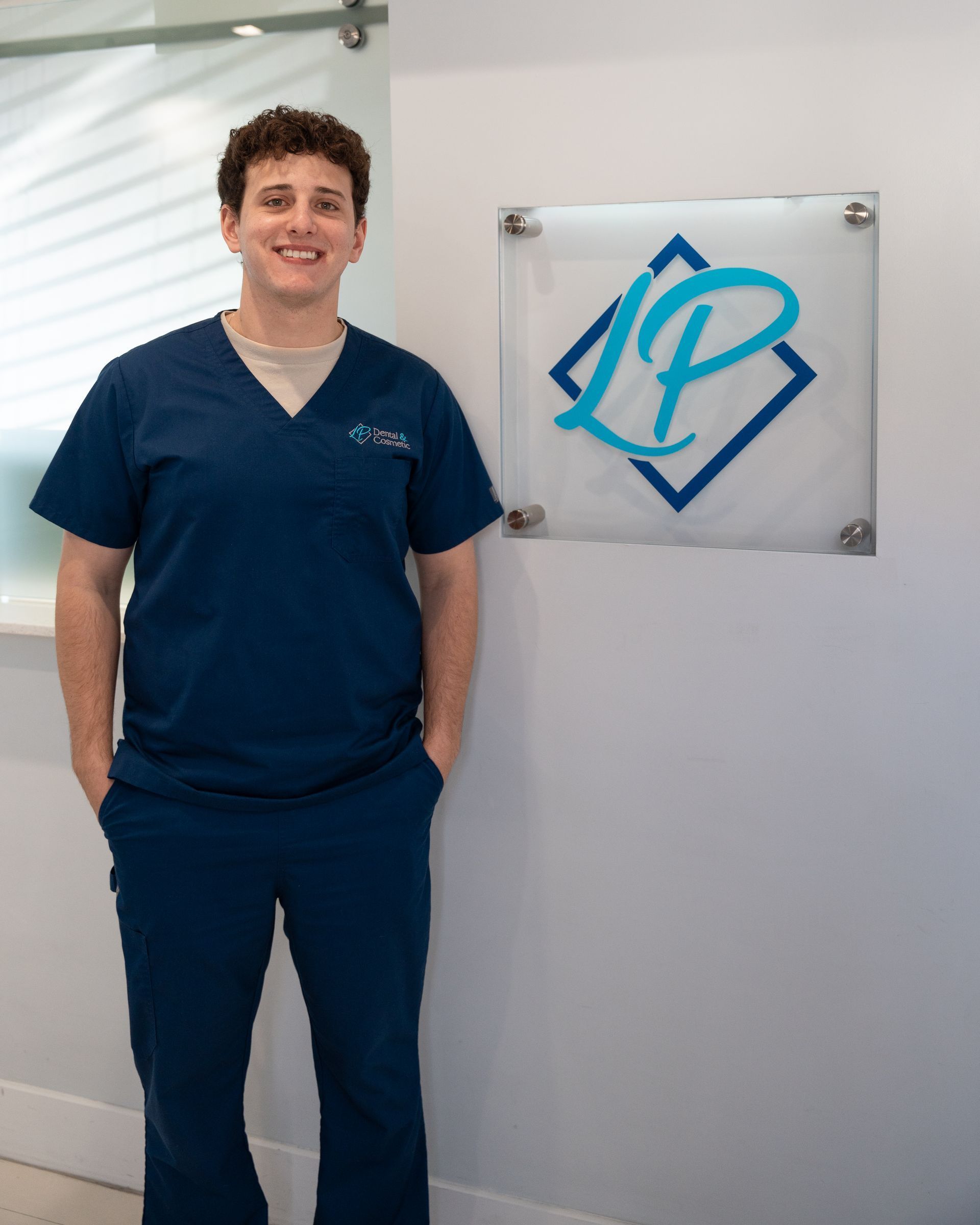 A man in scrubs is standing in front of a sign with the letter p on it