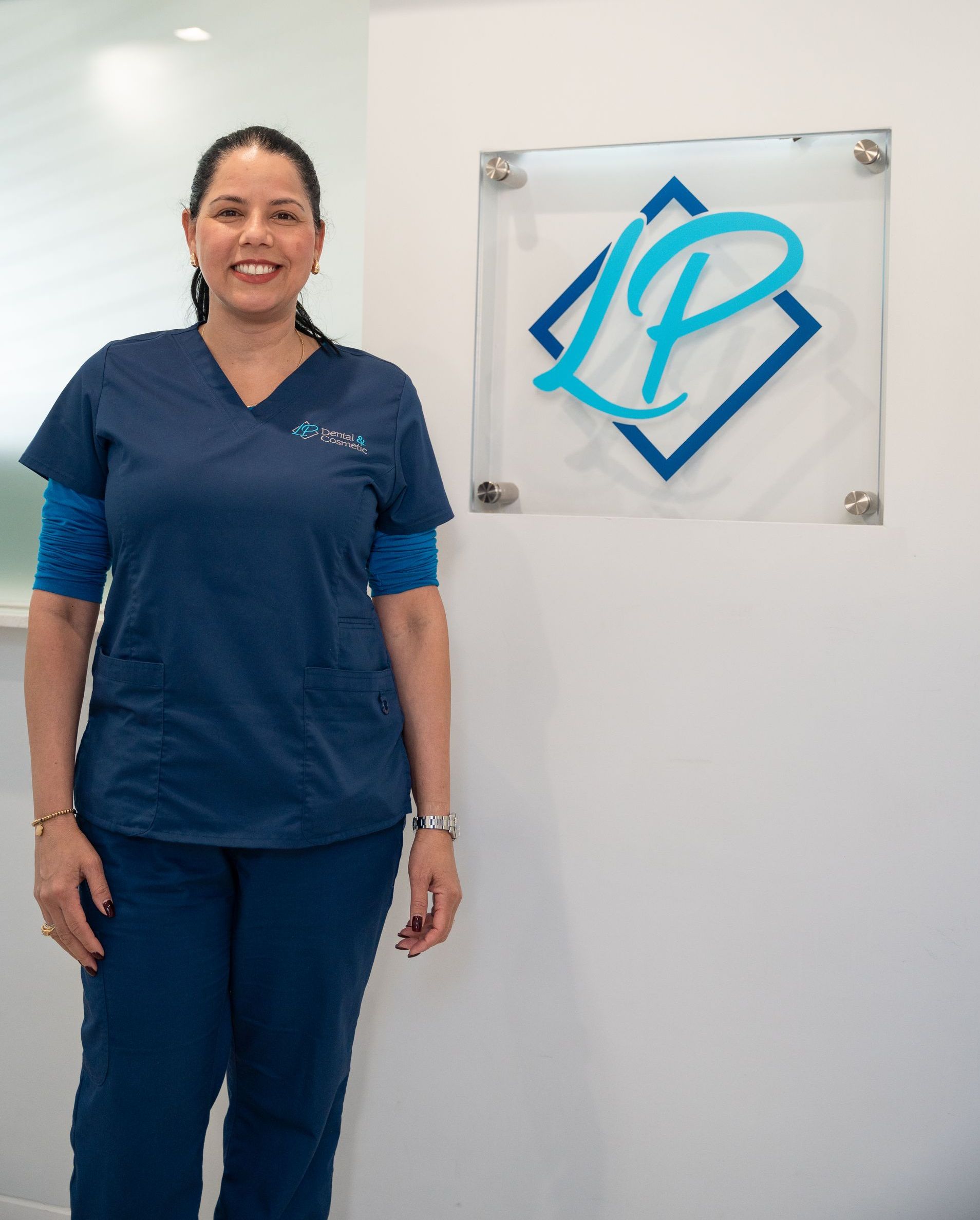 A woman in scrubs is standing in front of a sign that has the letter p on it