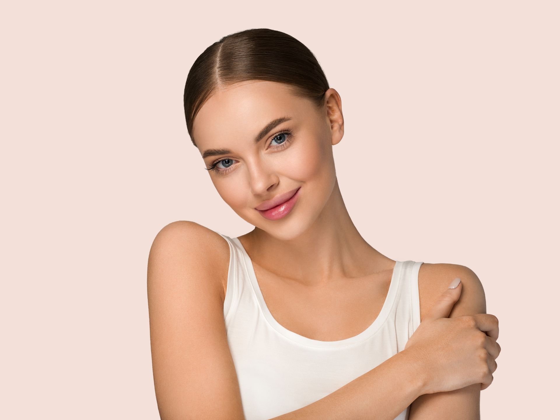 A woman in a white tank top is hugging herself.