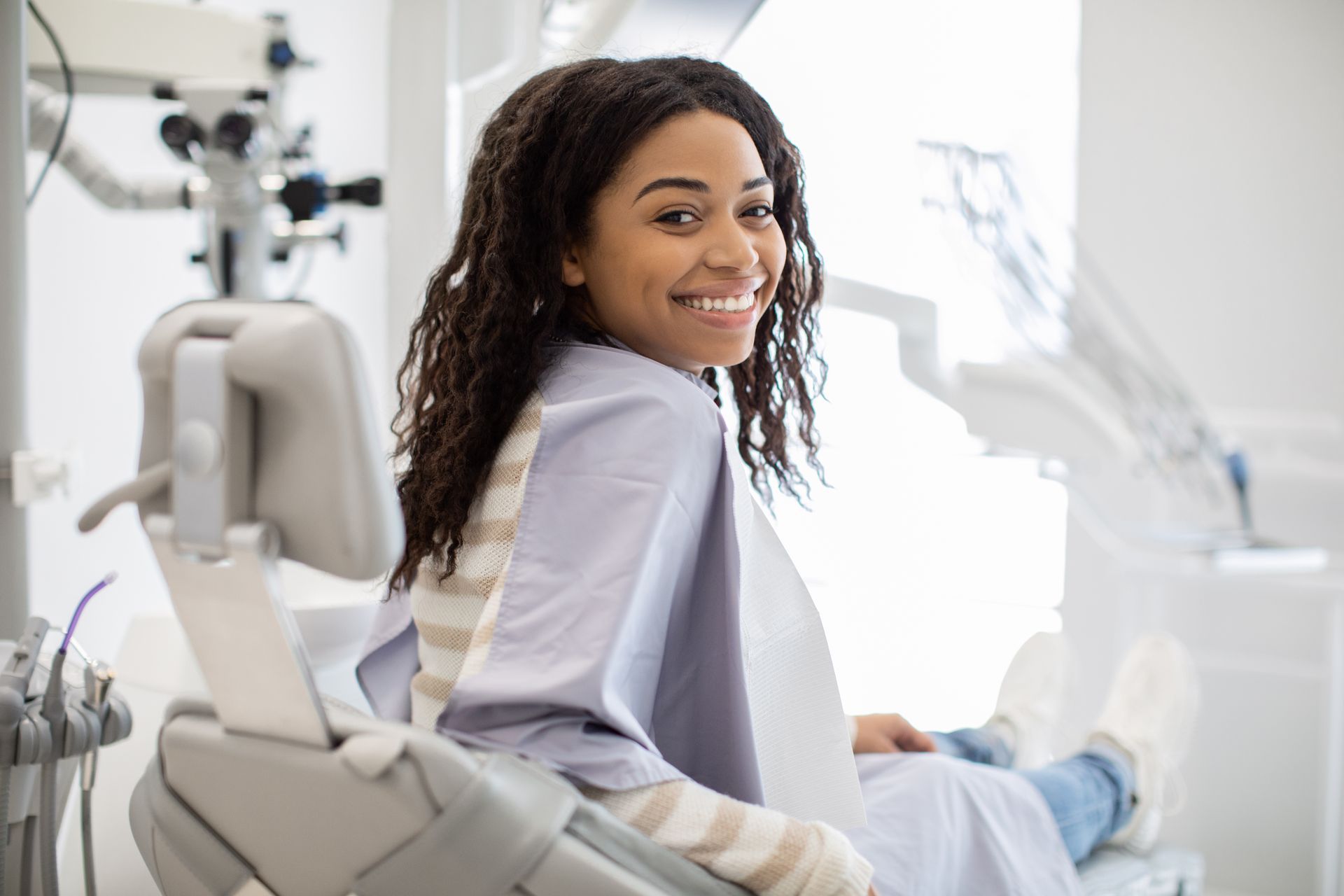 A woman is sitting in a dental chair and smiling.