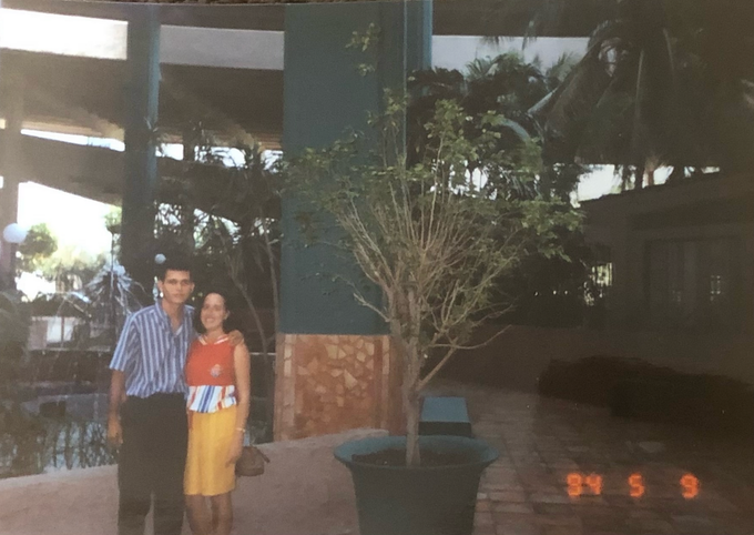 A man and a woman pose for a photo in front of a tree in a pot