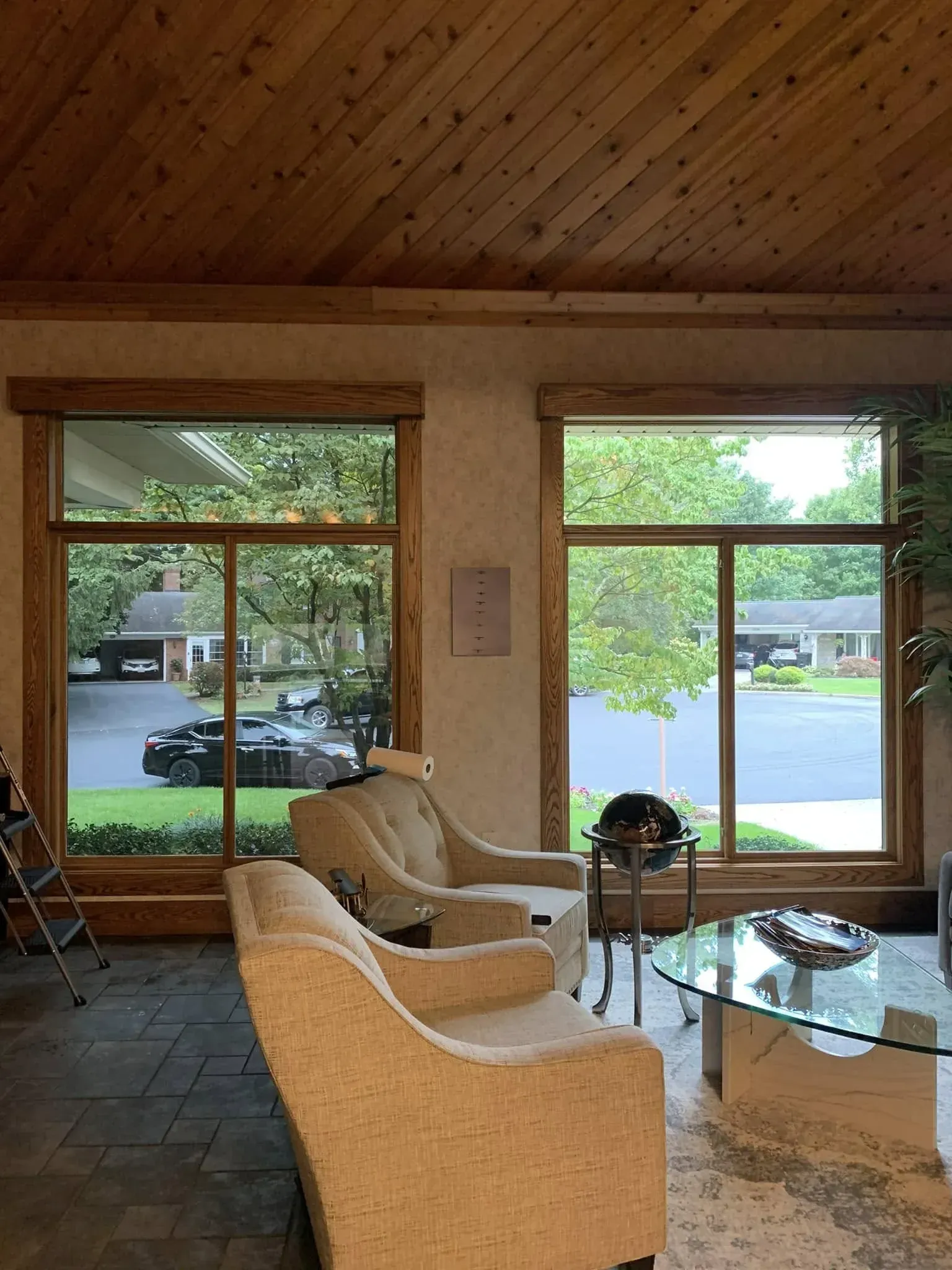 Interior with two windows, chairs, a table, and a wood ceiling.