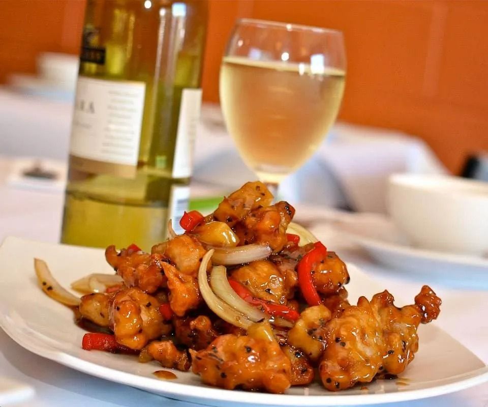 Plate of Sweet and Sour Chicken With a Glass and Bottle of White Wine — L'il Buddha Asian Cuisine in Salamander Bay, NSW