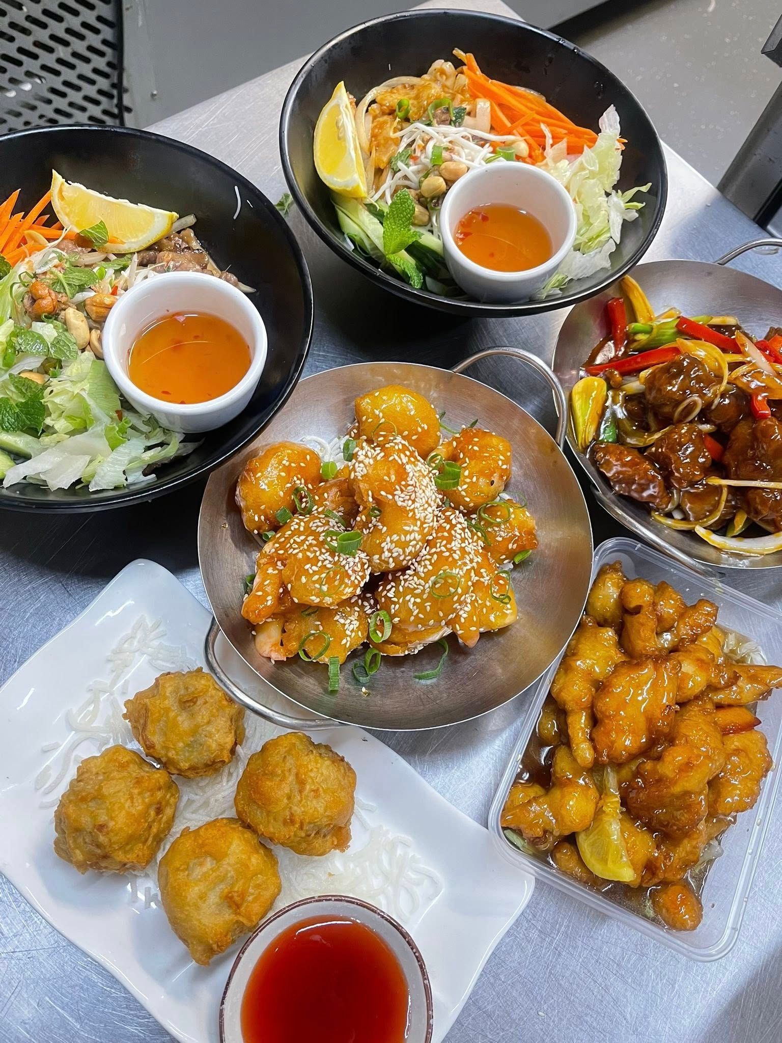 Several Asian dishes arranged on a table, including salad, tempura, and orange chicken— L'il Buddha Asian Cuisine in Salamander Bay, NSW