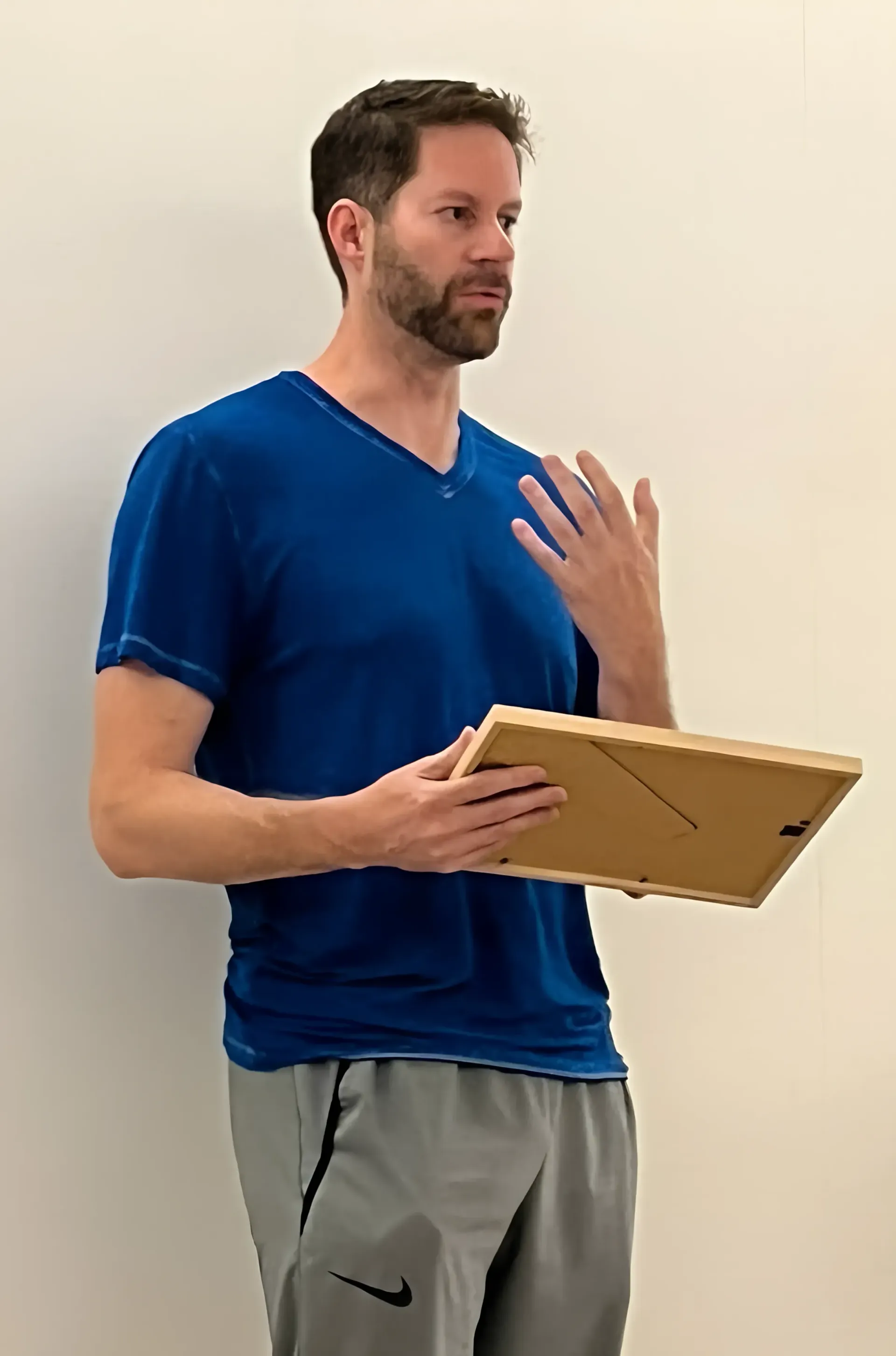 A man in a blue shirt is holding a picture frame.