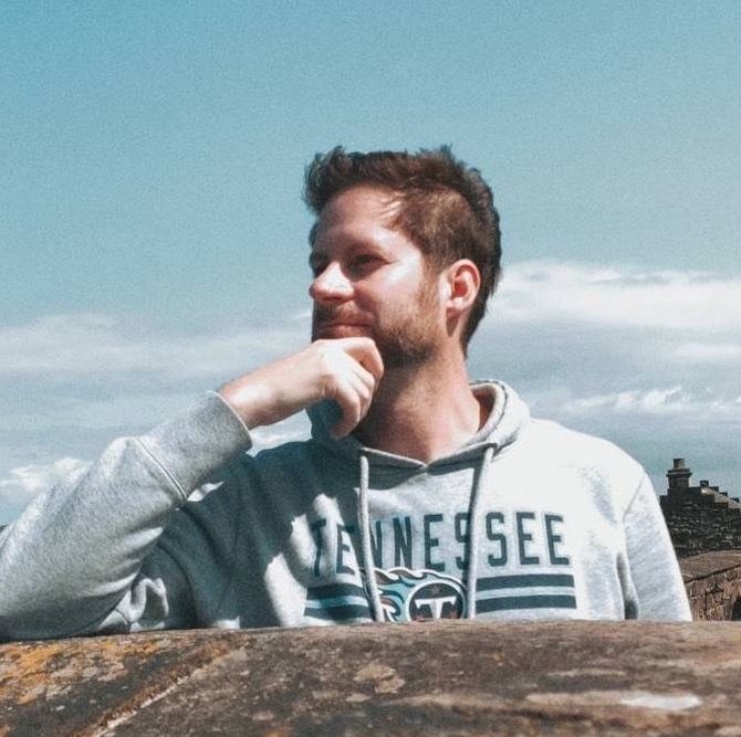 A man wearing a tennessee sweatshirt looks to the side