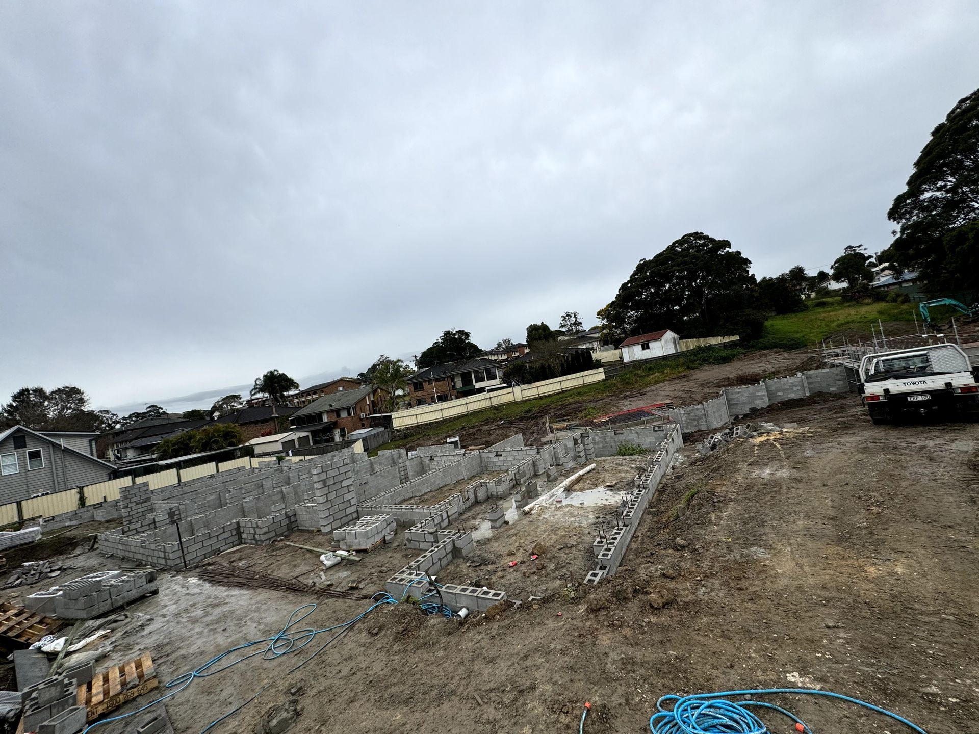 A construction site with a lot of dirt and a hose in the foreground.