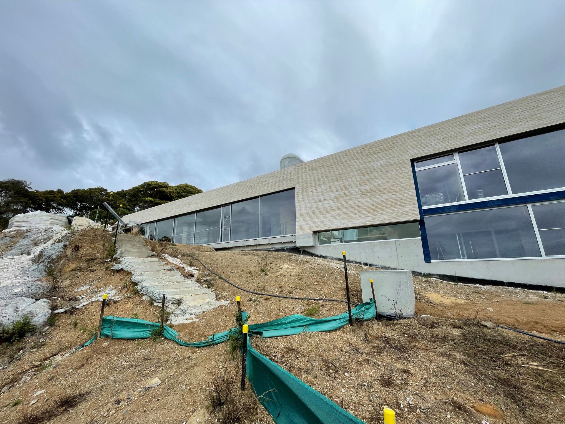 A large building is being built on top of a dirt hill.
