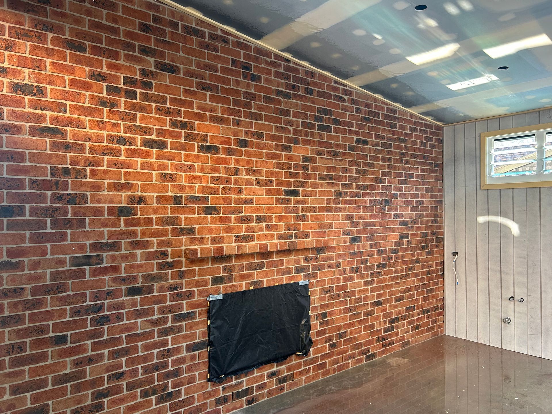 A living room with a brick wall and a fireplace.
