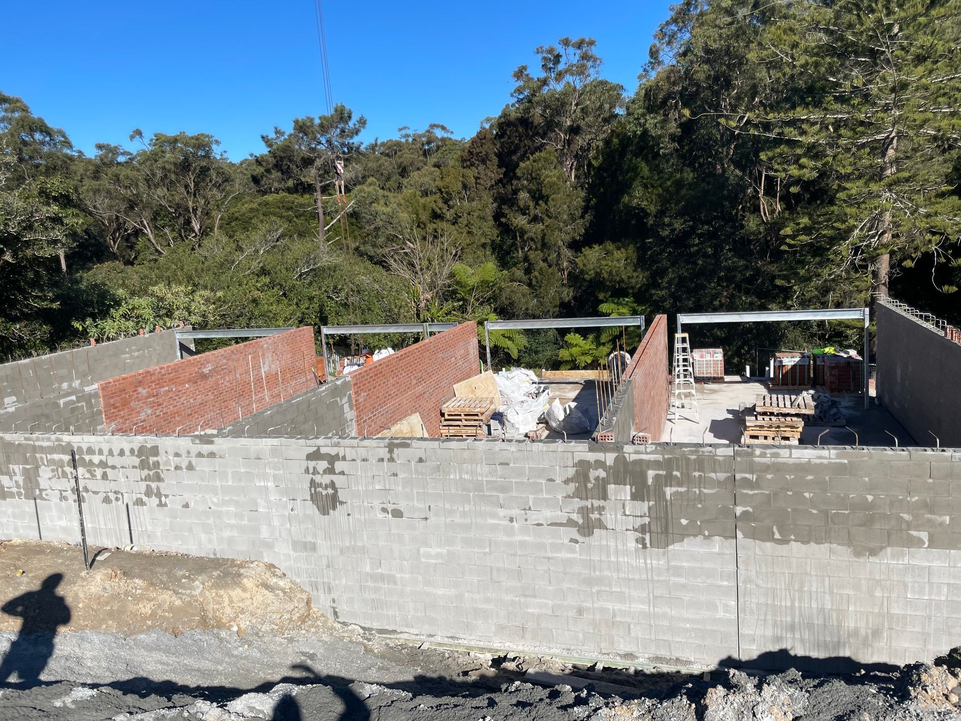 A brick wall is being built with trees in the background