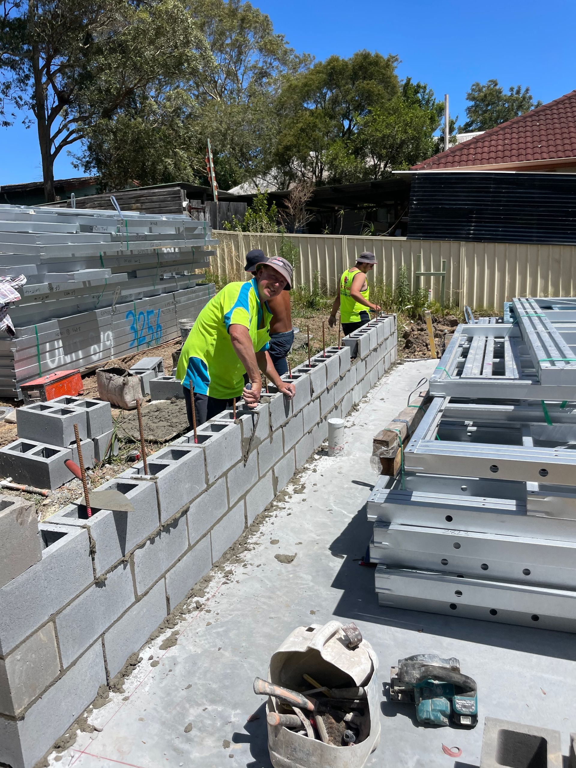 A brick wall is being built in front of a house.