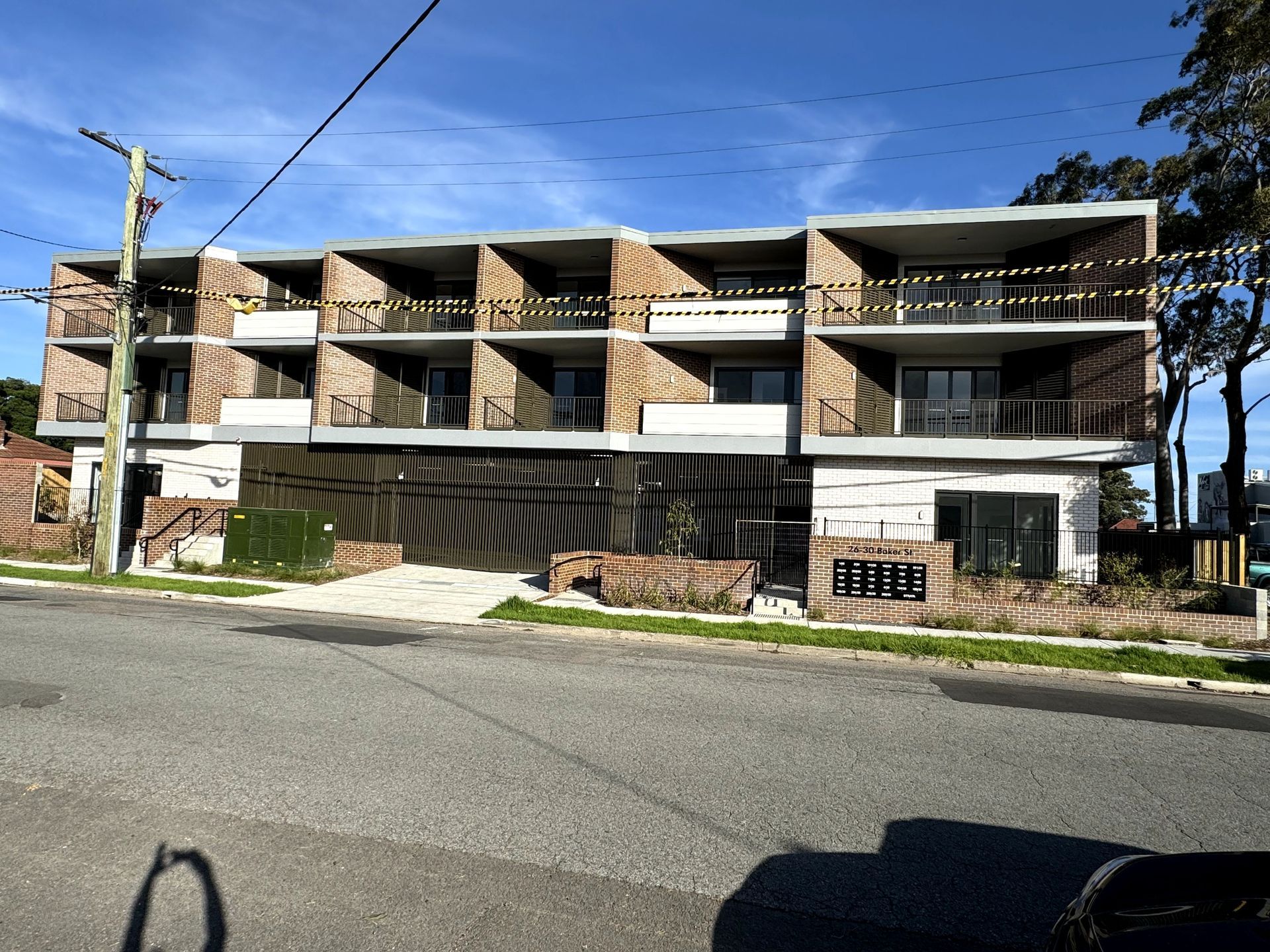 A large apartment building with balconies and a car parked in front of it.
