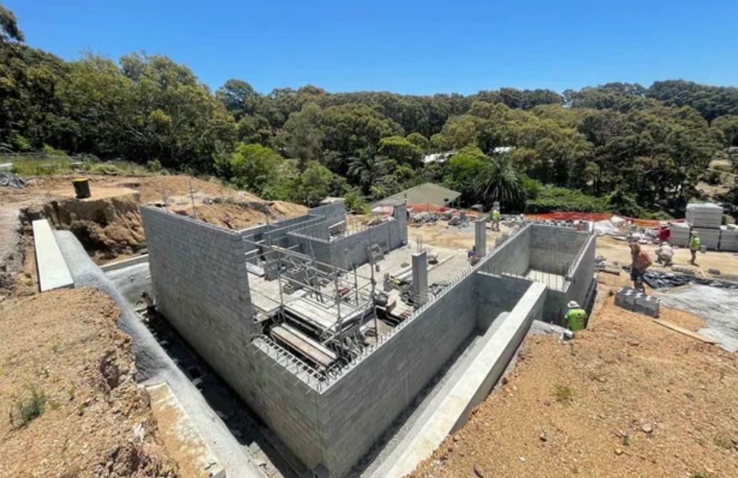 A large concrete structure is being built on top of a dirt hill.