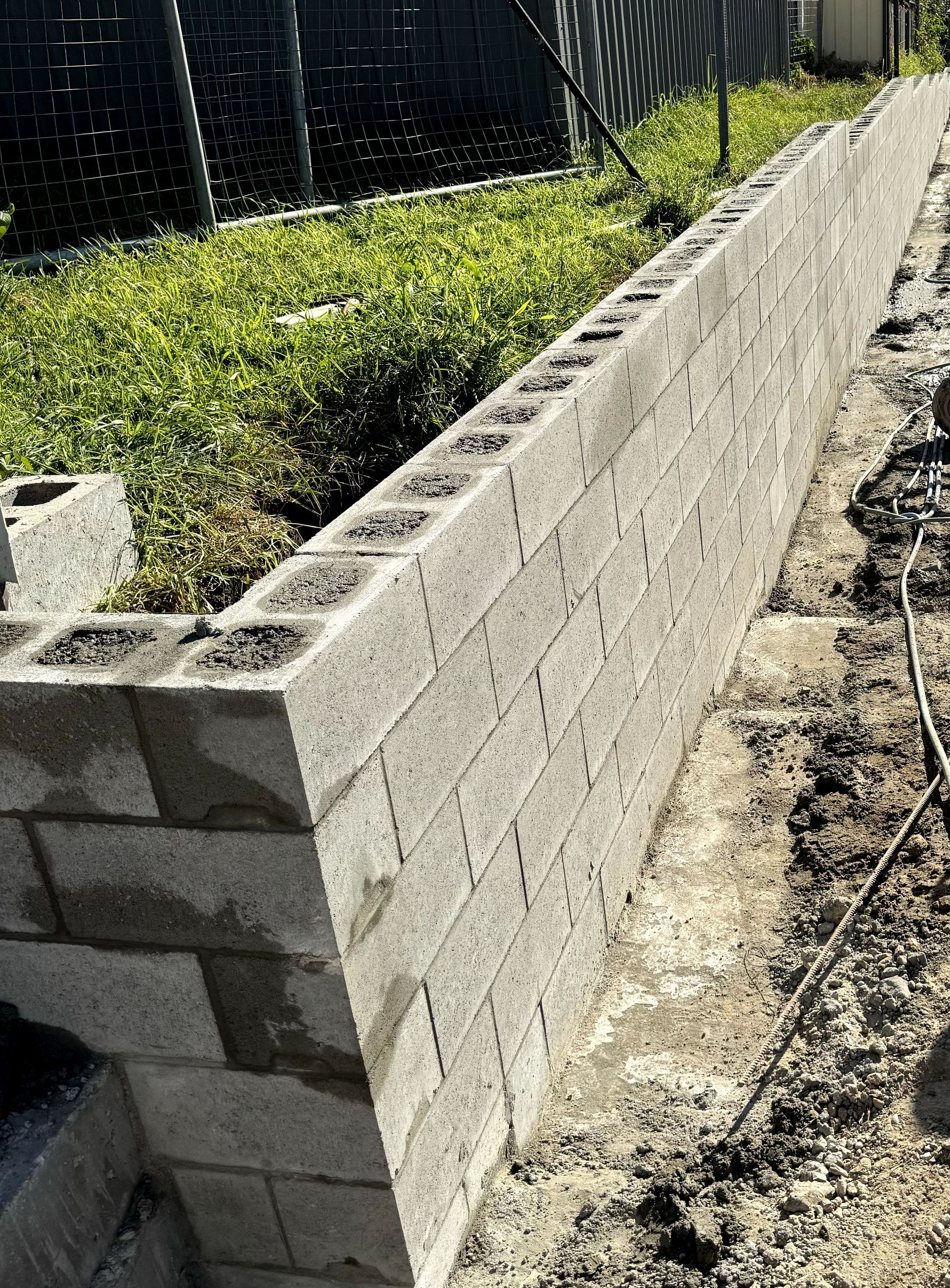 A brick wall is being built in a yard.