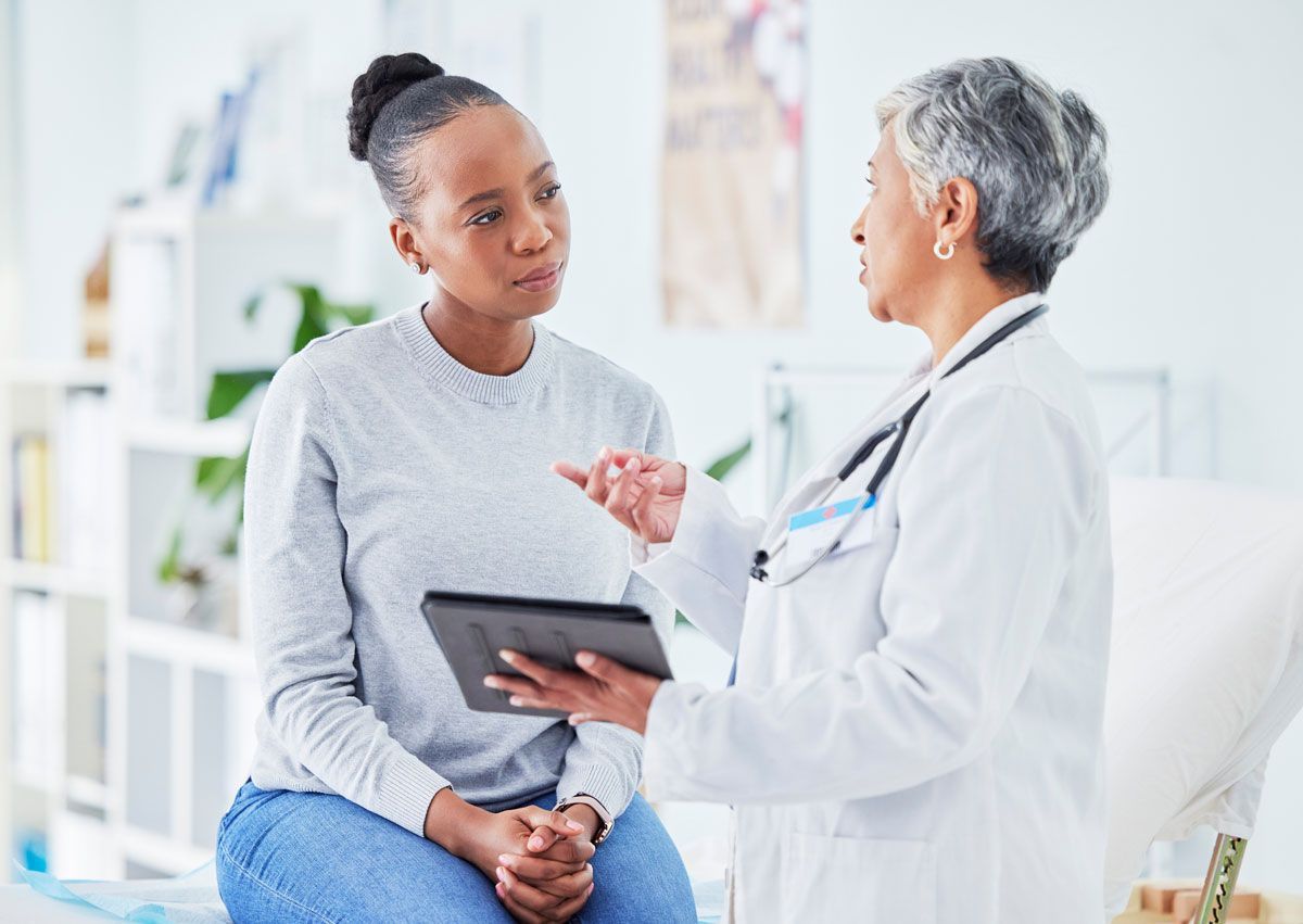 A doctor is talking to a patient while holding a tablet.