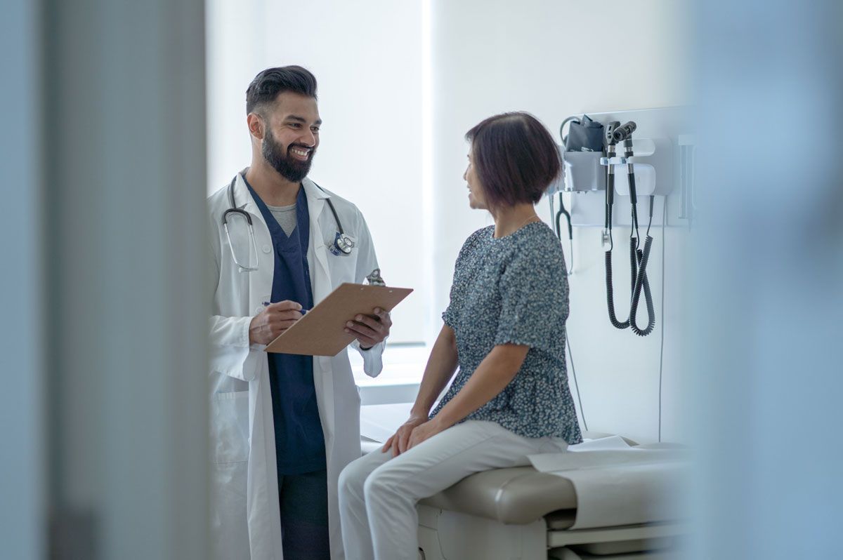 A doctor is talking to a patient who is sitting on an examination table.
