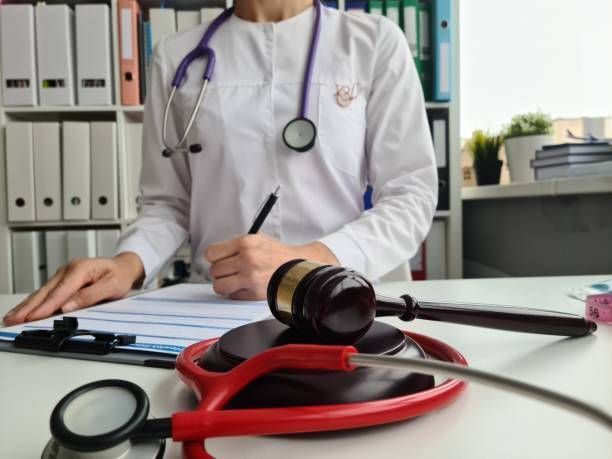 Judge’s gavel and a stethoscope in front of a doctor writing
