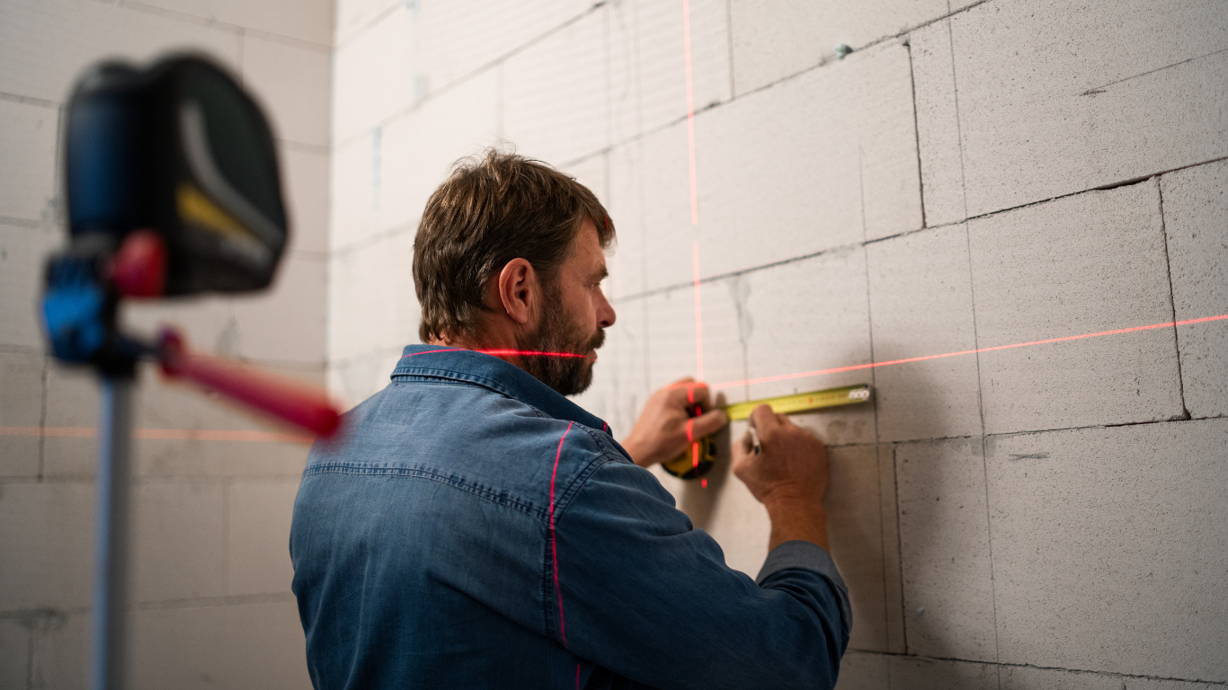 A man is measuring a wall with a tape measure.