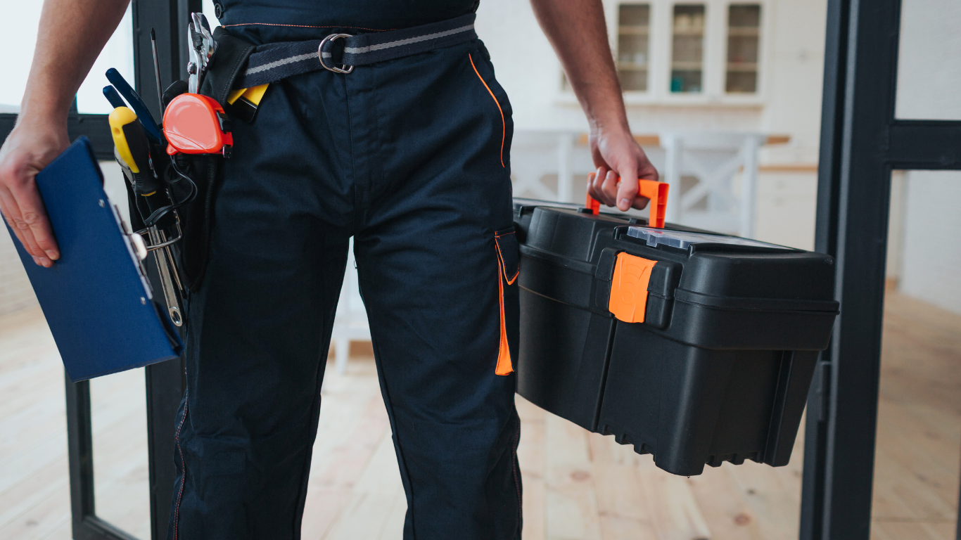 A man is holding a toolbox and a clipboard.