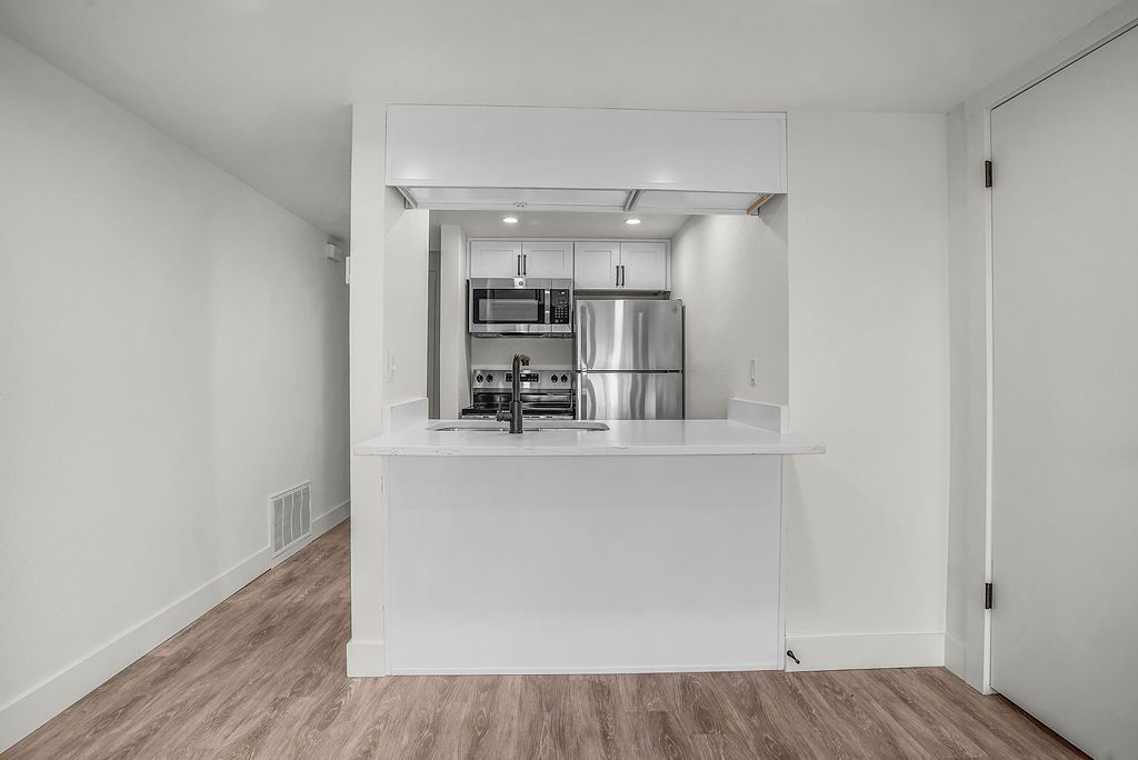 Modern kitchen with breakfast bar, stainless steel appliances, and white cabinets.