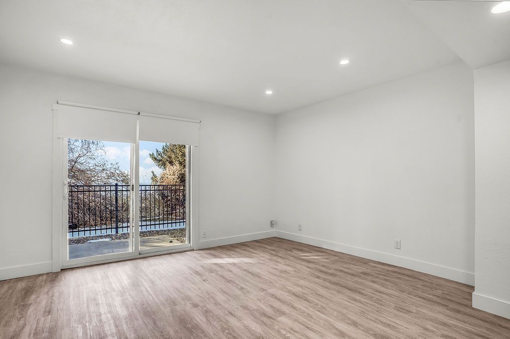 Empty room with sliding glass door, white walls, and wood-look flooring.