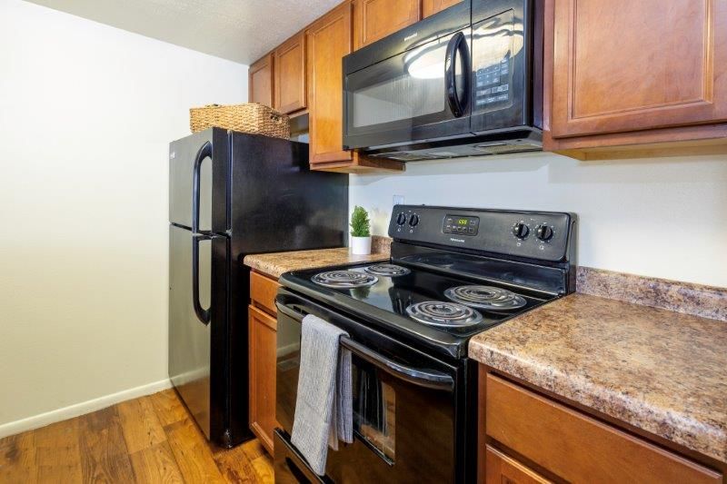 Kitchen with black appliances, wooden cabinets and countertops, and a microwave above the stove.