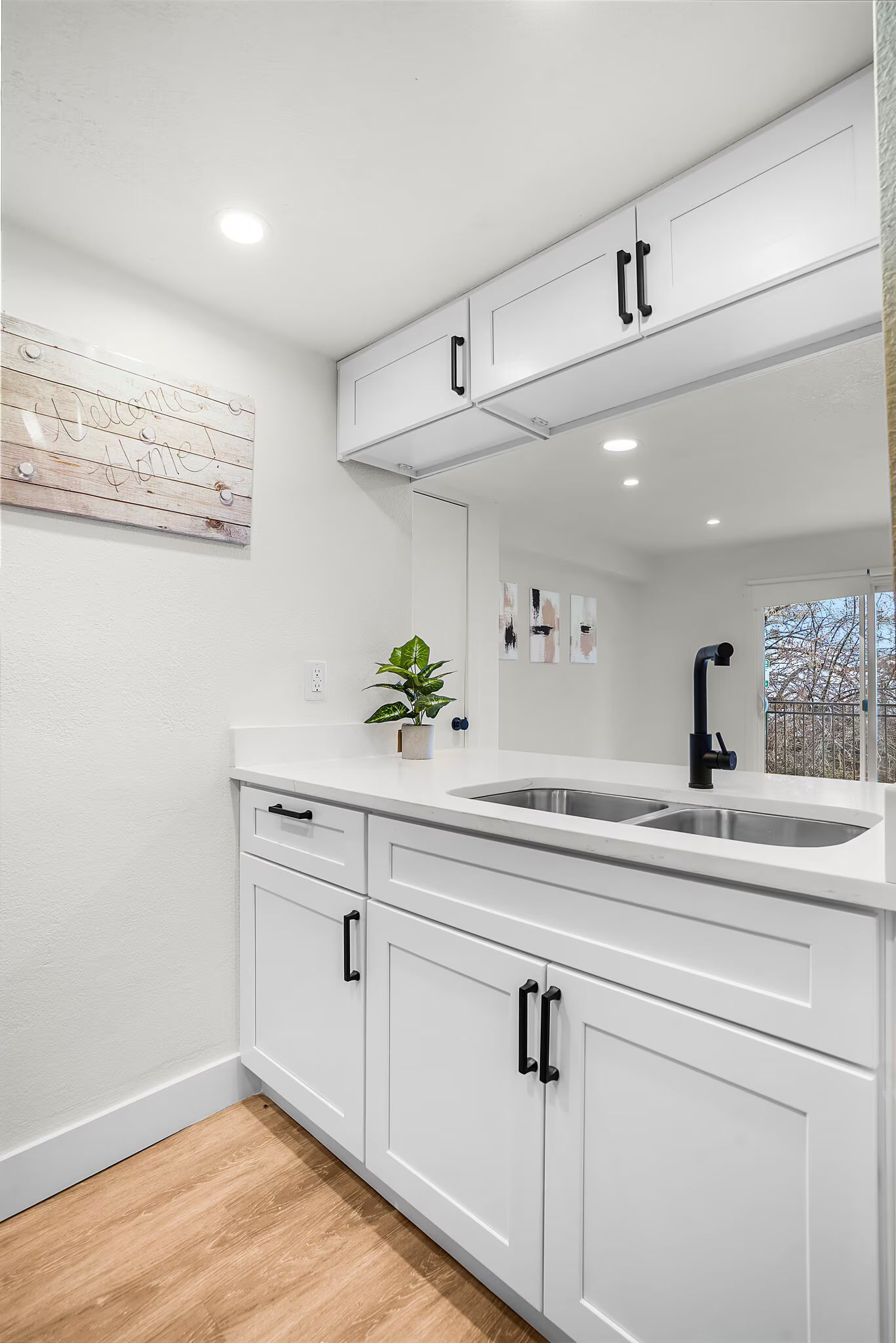 White kitchen cabinets with black hardware and a double sink.