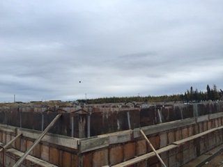 Un grand bâtiment en construction avec un ciel nuageux en arrière-plan.