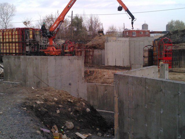 Une grue soulève un mur de béton sur un chantier de construction.