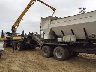 Un camion est chargé de béton par une grue.