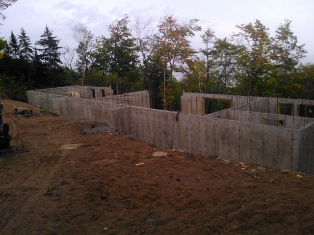 Un grand mur de béton est entouré d'arbres et de terre.