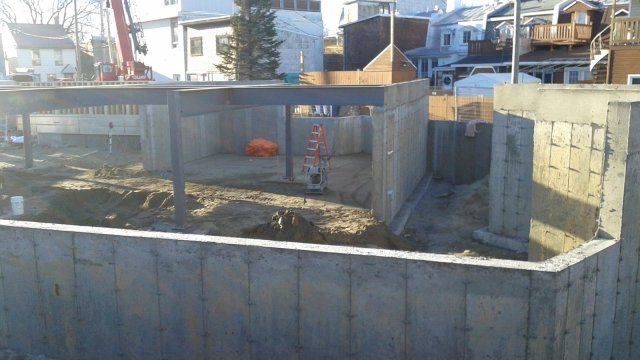 Un chantier de construction avec un mur de béton et une grue en arrière-plan.