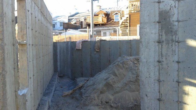 Un mur de béton est en construction à côté d'un tas de terre.