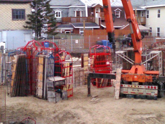 Un chantier de construction avec une grande grue orange et quelques bâtiments en arrière-plan