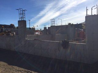 Un chantier de construction avec un mur de béton et un bulldozer en arrière-plan.