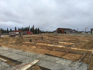 Un chantier de construction avec beaucoup de terre et un bâtiment en arrière-plan.