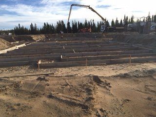 Une pompe à béton est utilisée pour couler du béton dans un champ de terre.