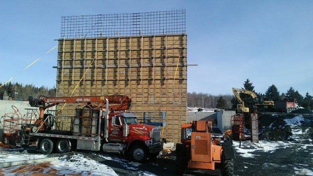 Un camion rouge est garé devant un bâtiment en construction.