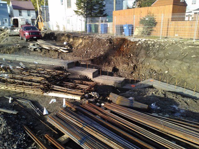 Un tas de tuyaux métalliques repose dans la terre près d'un chantier de construction