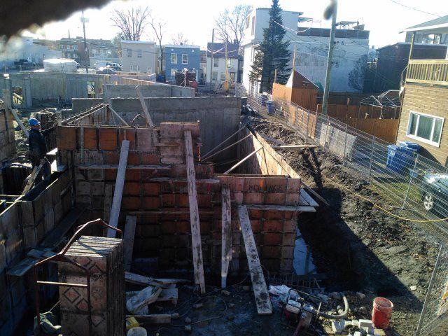 Un chantier de construction avec une clôture et quelques bâtiments en arrière-plan