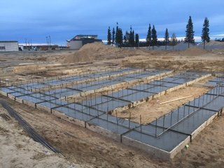 Une fondation en béton est en cours de construction dans un champ de terre.