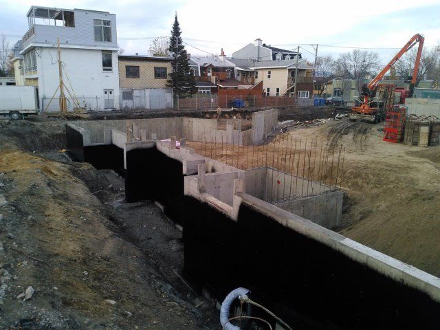 Un chantier de construction avec beaucoup de terre et quelques bâtiments en arrière-plan