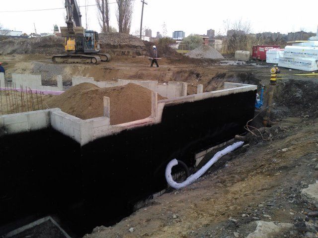 Un chantier de construction avec une grande excavatrice et un gros tas de terre.