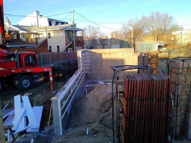 Un camion rouge est garé devant un bâtiment en construction