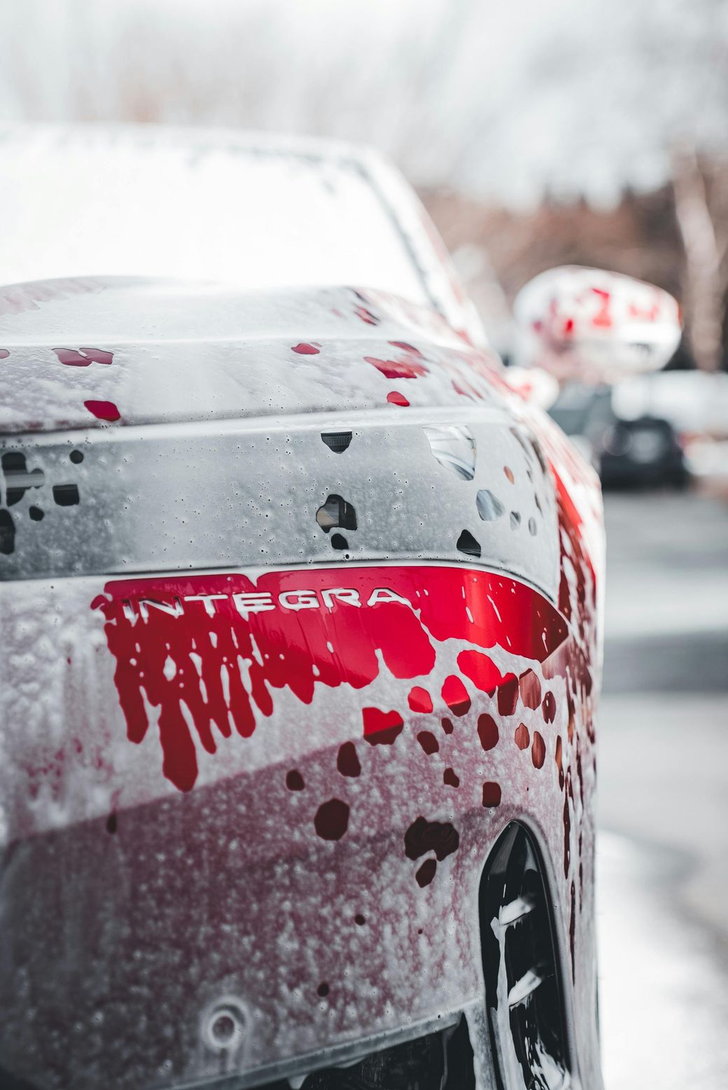 A red car is covered in soap and water.